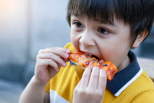 Foto retrato de niño comiendo pizza hecha en casa al aire libre café