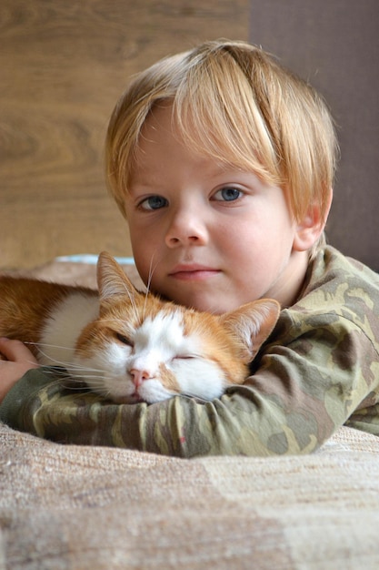 Retrato de un niño de cuatro años con gato rojo durmiendo