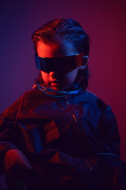 Retrato de niño cyberpunk con gafas vr en tonos azules y rojos con cables en un fondo rojo