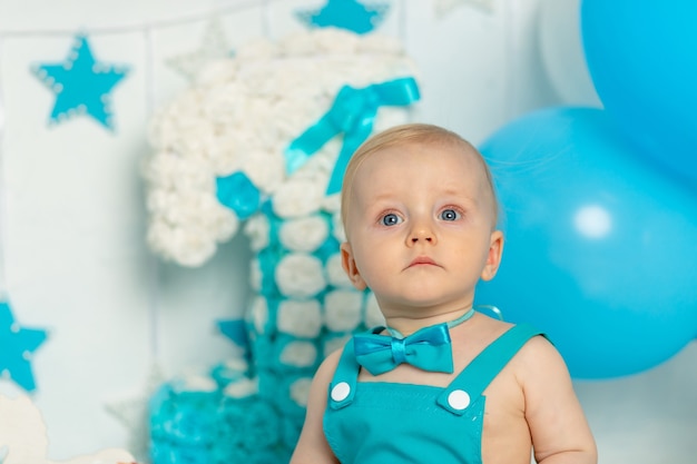 Foto retrato de niño en la decoración de la fiesta de cumpleaños de un año en azul con globos, concepto de vacaciones y decoración