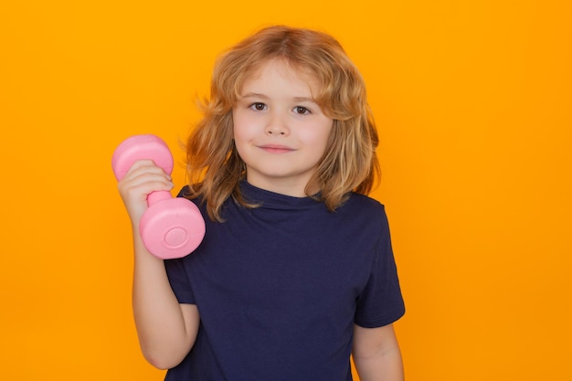 Retrato de niño deportivo con pesas aisladas sobre fondo amarillo de estudio actividades deportivas en