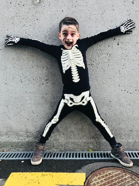 Foto retrato de un niño con disfraz de halloween de pie contra la pared