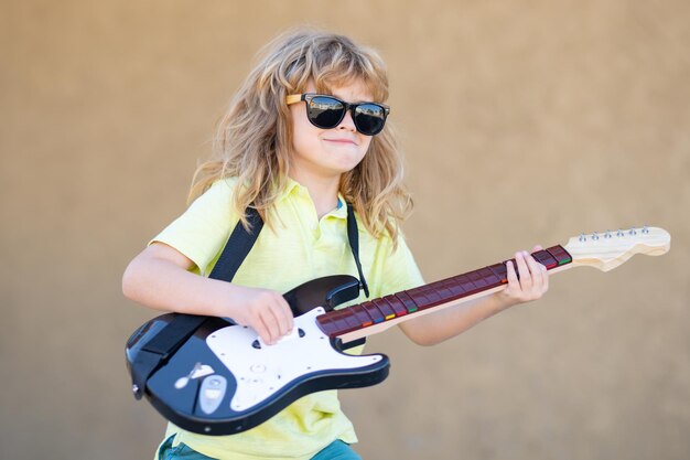 Retrato de un niño divertido con gafas practicando una canción durante una lección de guitarra en conc de música callejera