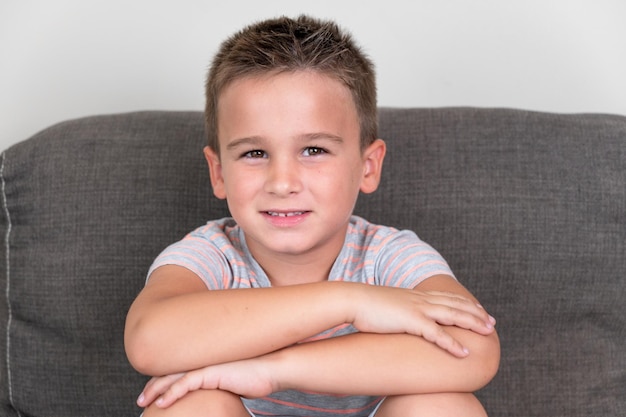 Retrato de un niño divertido sonriendo y riendo mirando a la cámara sentado en el sofá en casa Concepto de una infancia feliz