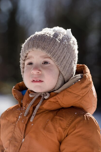 Retrato de un niño de dos años de edad de pie en la nieve fresca en invierno jugando al aire libre