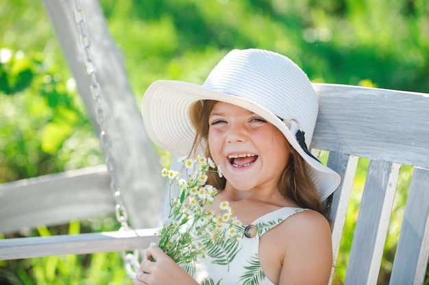 Retrato de un niño dulce disfrutando del aroma de las flores divirtiéndose en el parque de primavera Niño pequeño en el prado con flores silvestres Niño feliz al aire libre en el campo de primavera