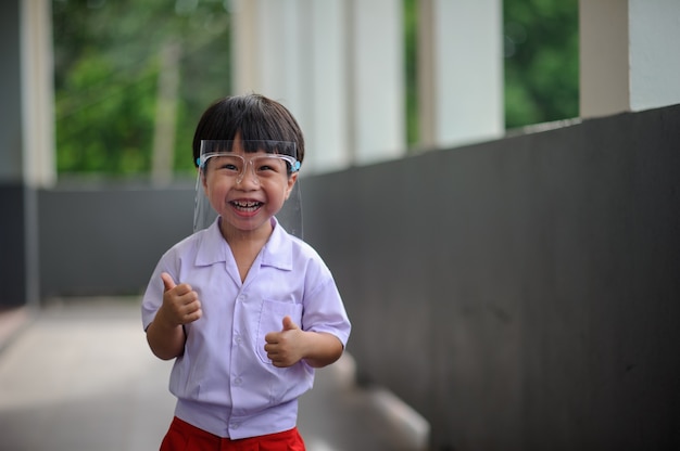 Retrato de niño en edad preescolar sonriente con protector facial nuevo estilo de vida normal en lugares públicos.