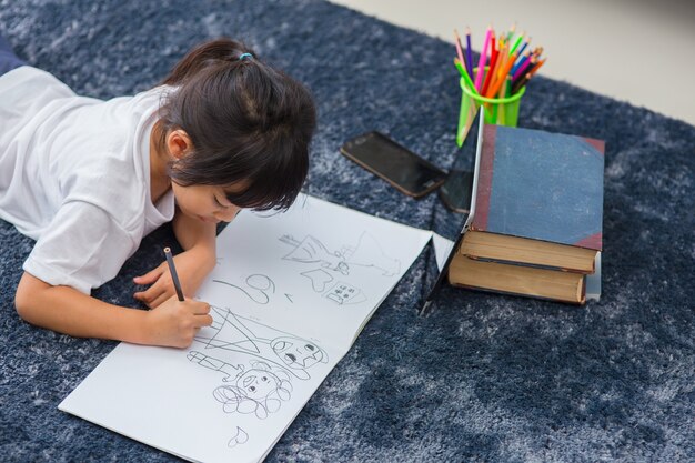 Retrato de niño en edad preescolar con tableta para su tarea, enfoque suave del niño haciendo la tarea mediante el uso de tableta digital que busca información en internet, e-learning o concepto de educación escolar en el hogar