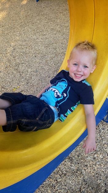 Retrato de un niño feliz acostado en el patio de recreo