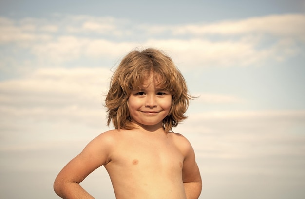 Retrato de niño feliz sin camisa sonriendo verano al aire libre cielo fondo chico