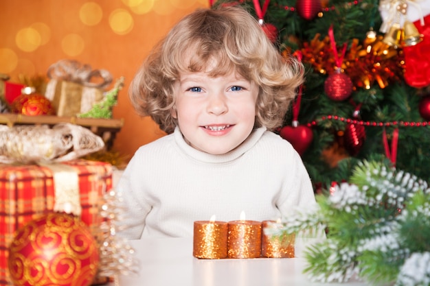 Retrato de niño feliz contra el árbol de Navidad con adornos