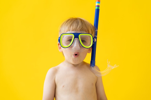 Retrato de niño feliz contra la pared amarilla en vacaciones de verano.