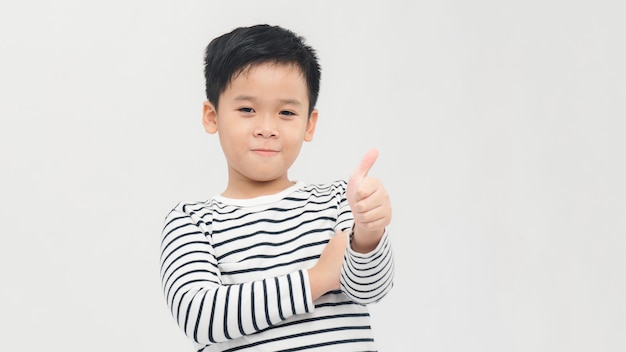 Retrato de niño feliz mostrando Thumbs up gesto aislado sobre fondo blanco.