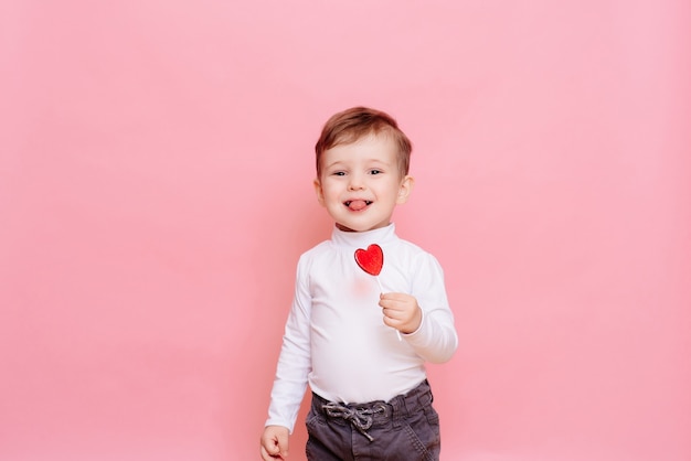 retrato de un niño feliz con una piruleta en forma de corazón.