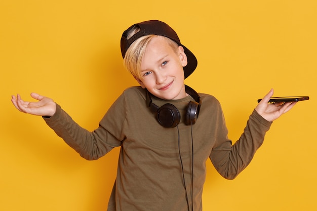 Retrato de niño feliz sonriente de pie con las manos extendidas aisladas sobre amarillo