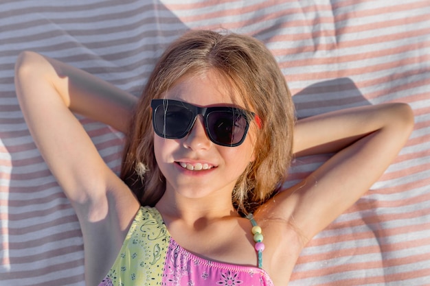 Foto retrato de un niño feliz en una toalla de playa con gafas vista superior