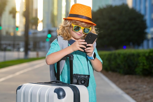 Retrato de niño feliz viajero con equipaje Pequeño turista positivo con maleta lista para viajar Niño feliz turista con equipaje que va a viajar de vacaciones