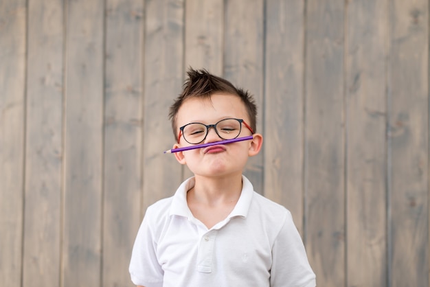 Foto retrato de niño con gafas y camiseta blanca en la superficie de madera