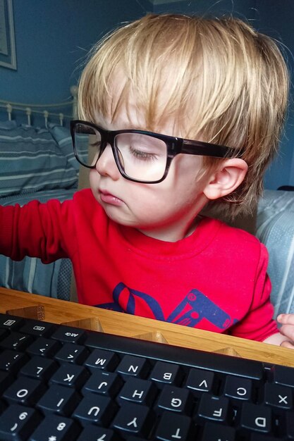 Foto retrato de un niño con gafas trabajando desde casa