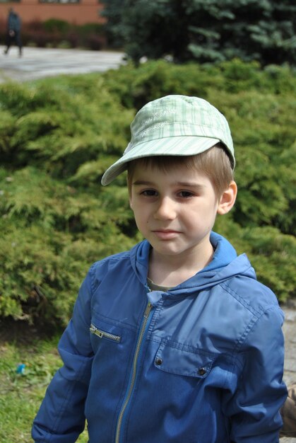 Retrato de un niño con gorra de pie contra las plantas