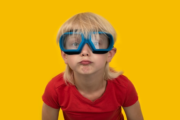 Retrato de niño gracioso en gafas protectoras en amarillo