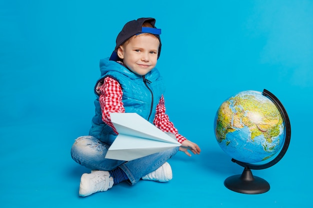 Retrato de niño gracioso con gorra y avión de papel de juguete