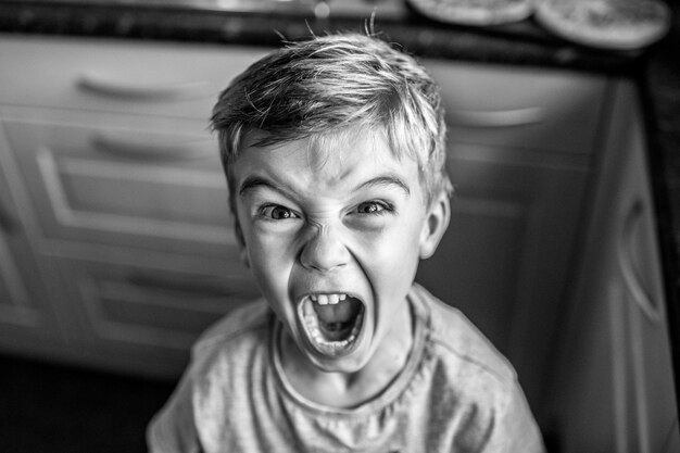 Retrato de un niño gritando en casa