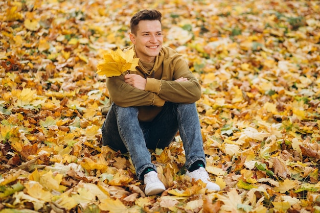 Retrato de niño guapo y feliz con un ramo de hojas amarillas sonriendo