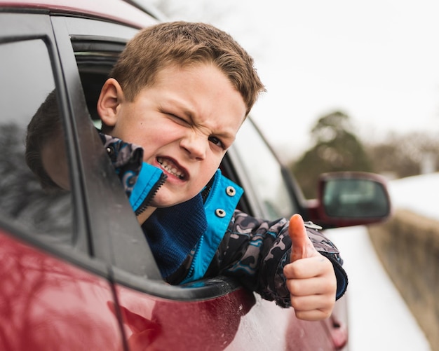 Foto retrato de un niño guiñando el ojo mientras viaja en coche