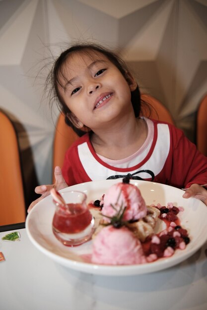 Foto retrato de un niño con helado de fresa en un plato