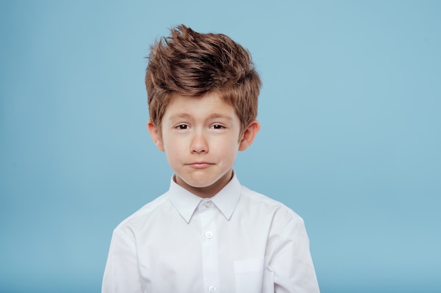 Retrato de niño hermoso mirar la cámara aislada sobre fondo azul