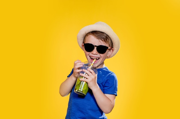 Retrato de un niño hermoso. Niño feliz. Niño europeo con sombrero, camiseta de verano con limonada. Verano, vacaciones, vacaciones, sol, calor, mar, playa. Cara para publicidad.