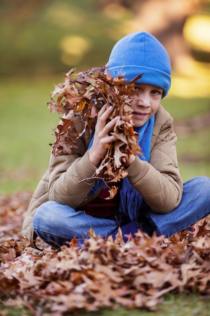 Retrato de niño con hojas de otoño en el parque