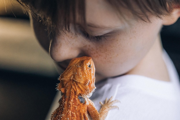 Retrato de niño con iguana Agama barbuda roja Niño pequeño jugando con reptil Enfoque selectivo