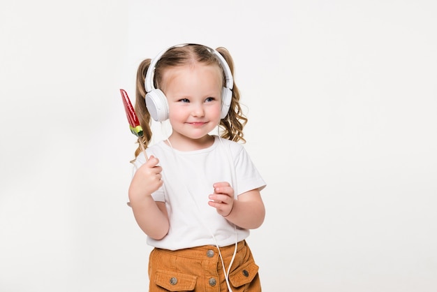 Retrato, de, niño joven, niña, en, auricular, comer, dulces