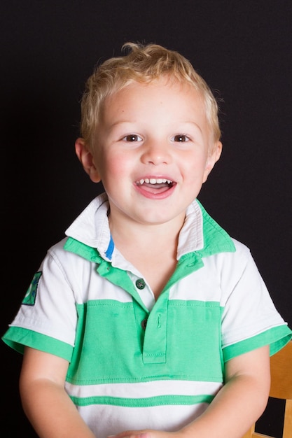 retrato, de, niño joven, sonriente, en, fondo negro