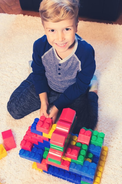 Foto retrato de un niño jugando con bloques de juguete coloridos en casa