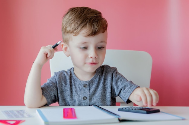 Retrato de niño lindo en casa haciendo la tarea Niño pequeño concentrado escribiendo con lápiz de colores en el interior Escuela primaria y educación Niño aprendiendo a escribir letras y números