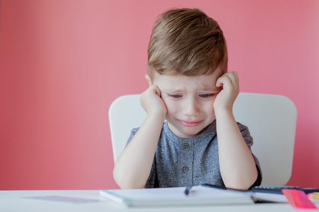 Retrato de niño lindo en casa haciendo la tarea Niño pequeño concentrado escribiendo con lápiz de colores en el interior Escuela primaria y educación Niño aprendiendo a escribir letras y números