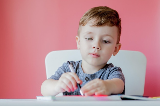 Retrato de niño lindo en casa haciendo la tarea Niño pequeño concentrado escribiendo con lápiz de colores en el interior Escuela primaria y educación Niño aprendiendo a escribir letras y números