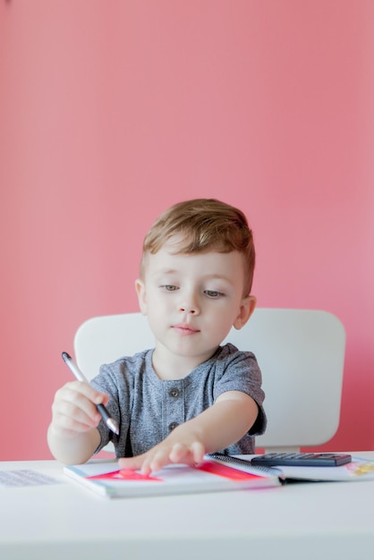 Retrato de un niño lindo en casa haciendo la tarea Un niño poco concentrado escribiendo con lápiz de colores en el interior Escuela primaria y educación Niño aprendiendo a escribir letras y números