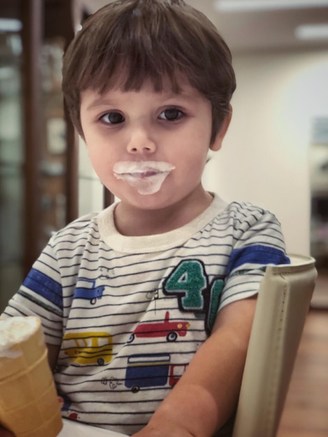 Foto retrato de un niño lindo comiendo helado mientras está sentado en una silla en casa