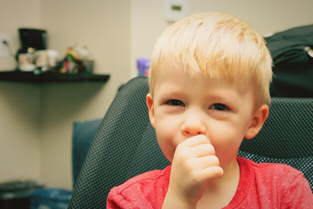 Foto retrato de un niño lindo con el dedo en la boca en casa