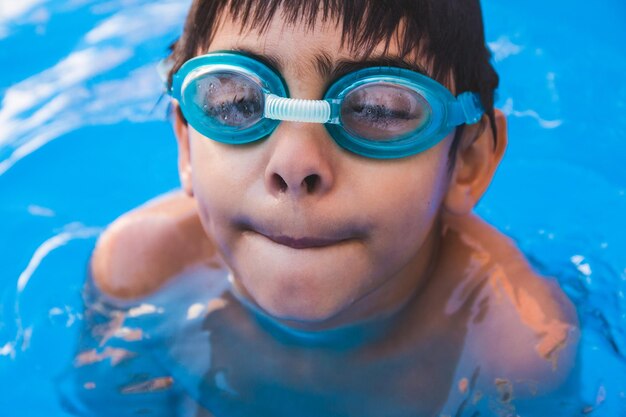 Foto retrato de un niño lindo con gafas de natación en la piscina