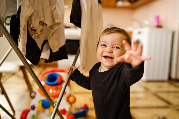 Retrato de niño lindo en el interior de la casa secando la ropa ayuda con las tareas del hogar