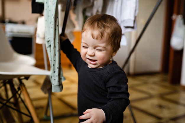 Retrato de niño lindo en el interior de la casa secando la ropa ayuda con las tareas del hogar