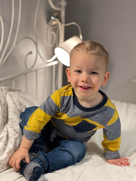 Retrato de un niño lindo sentado en la cama en casa