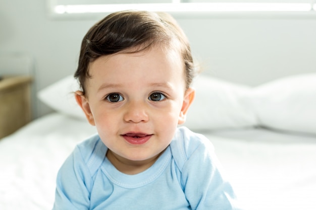 Foto retrato de niño lindo sentado en la cama