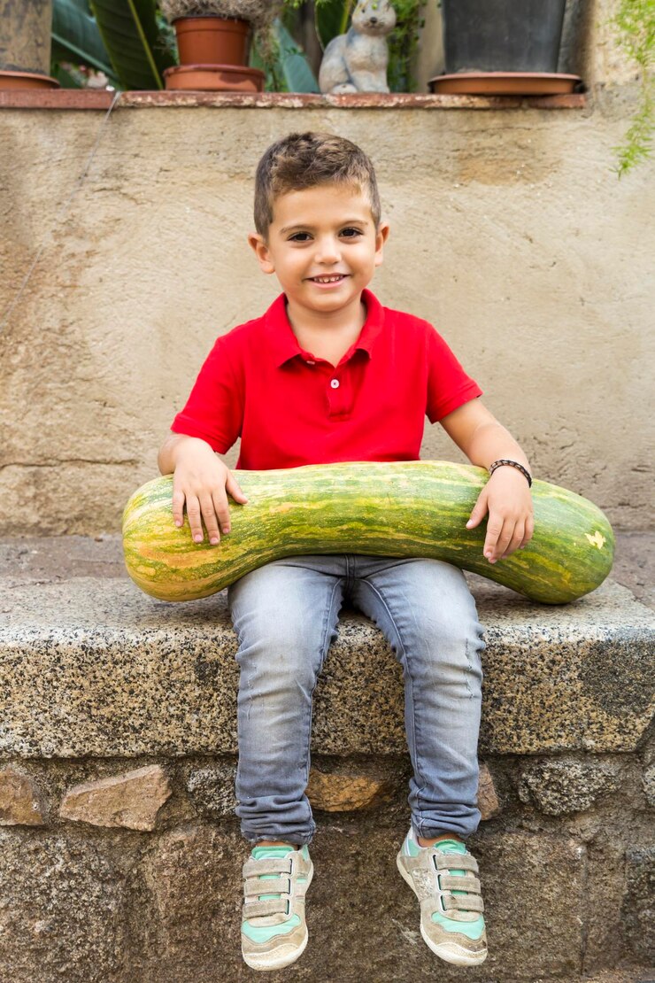 Foto retrato de un niño lindo sonriente sosteniendo una calabaza mientras está sentado en la pared de contención