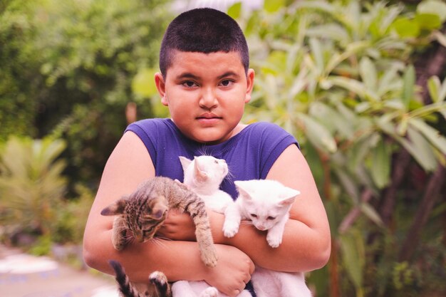 Foto retrato de un niño lindo sosteniendo gatos